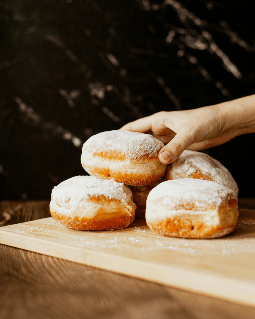 a hand reaching for stuffed donuts on a cutting board