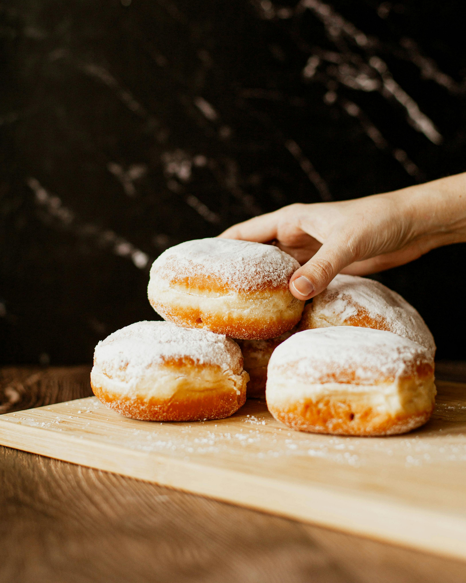 reaching-for-donuts a hand reaching for stuffed donuts on a cutting board