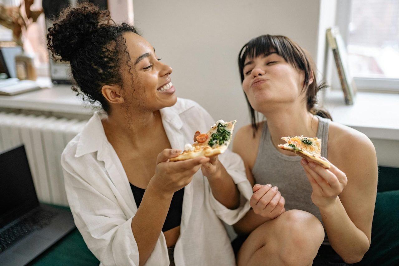 Two happy, young girls enjoying food after they've healed from diet culture