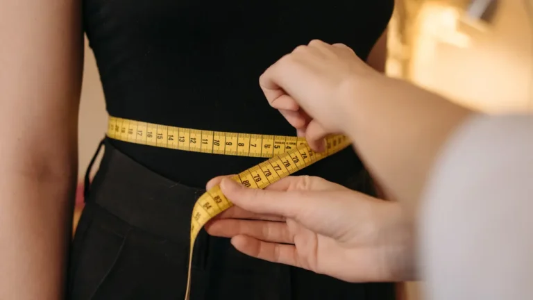 An image of a women in a black outfit with a measuring tape around her waist, emphasizing what many people only consider weight when dieting, not what actually happens in your body